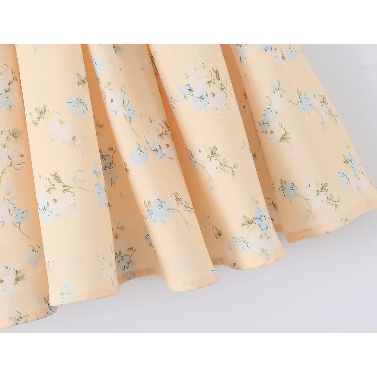 Close-up of the skirt hem and gathered fabric on a peach floral print dress.
