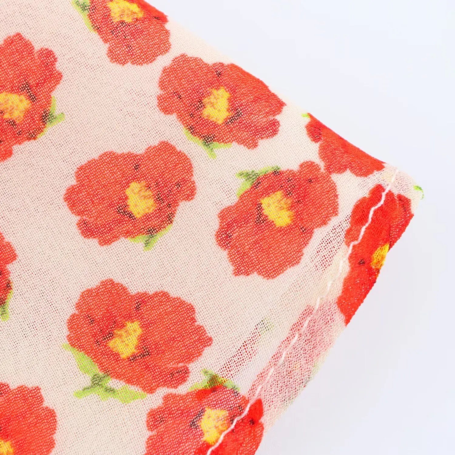 Close-up of the orange floral print on the lightweight chiffon fabric of the peach dress