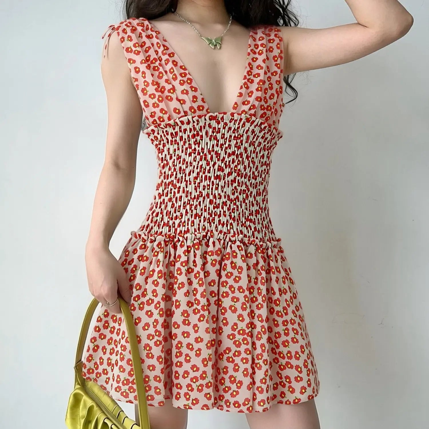 Lifestyle shot of model wearing the peach floral chiffon dress, showing the deep V-neck and smocked waist