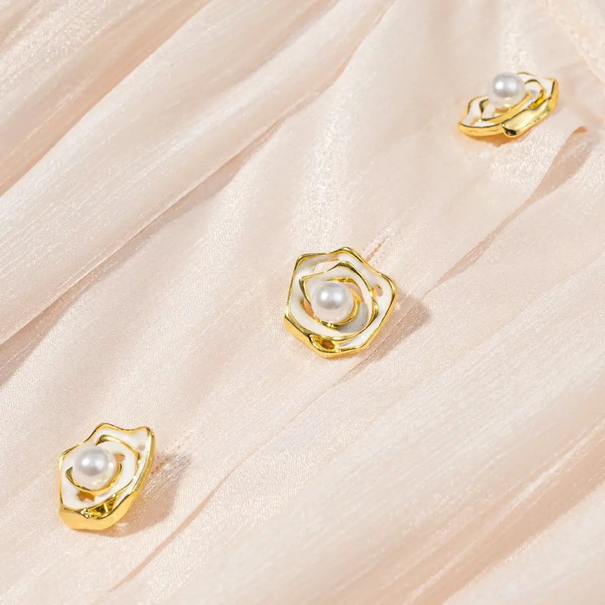 Close-up of the decorative gold rose buttons with pearls on the peach iridescent dress