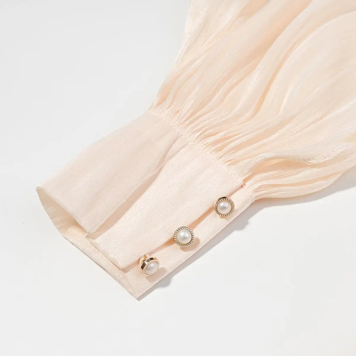 Cuff detail of peach iridescent dress, showing the gathered sleeve and pearl buttons