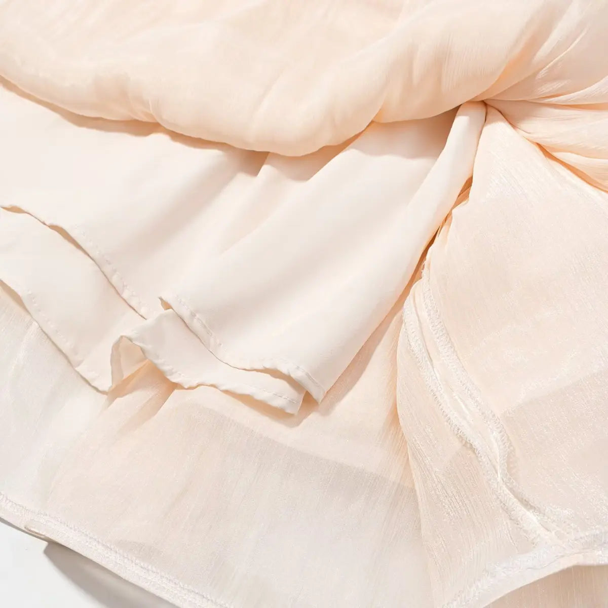Close-up of peach iridescent dress fabric, showing the layered lining and sheer texture
