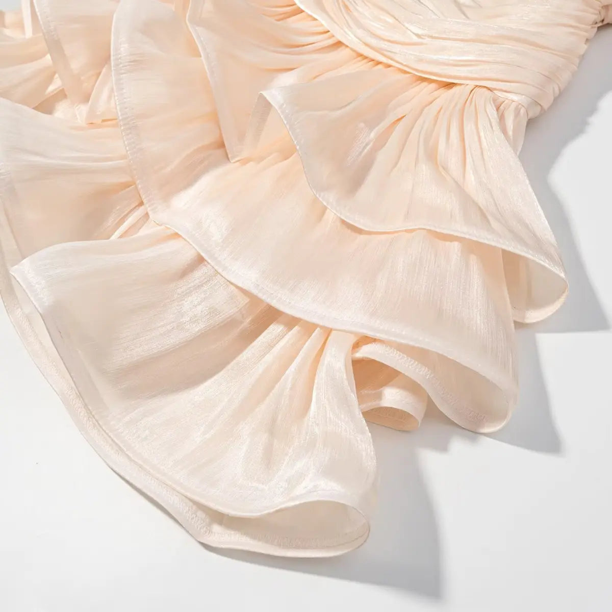 Skirt detail of peach iridescent dress, showing the tiered ruffle hem and flowing texture