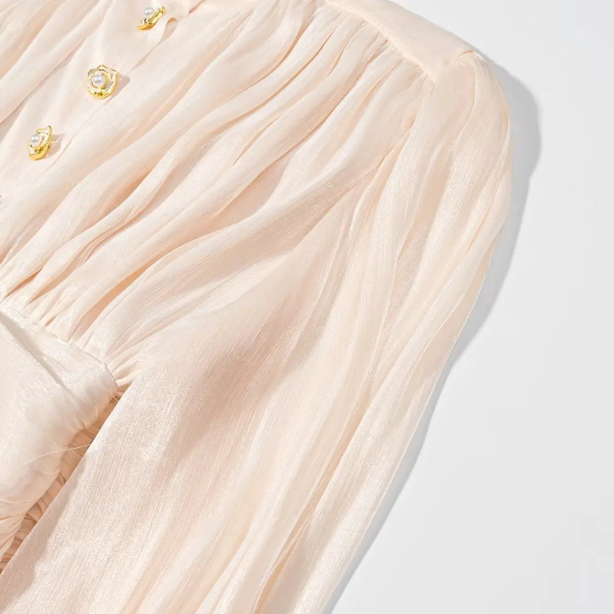 Sleeve and bodice detail of peach iridescent dress, showing the gathered fabric and decorative buttons