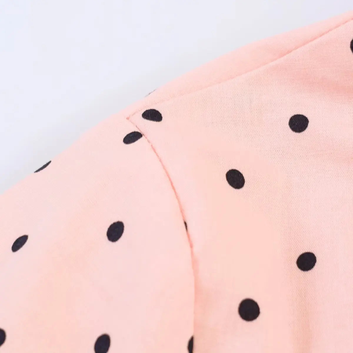 Shoulder and sleeve seam detail of the peach polka dot top, showing the stitching and fabric texture