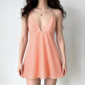 Woman wearing peach white vertical stripe deep v flowy spaghetti strap mini dress