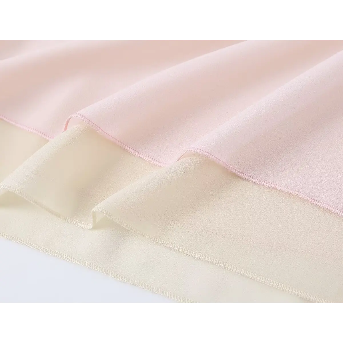 Close-up view of pink and beige tiered chiffon skirt fabric, showcasing soft texture and finished edge stitching.