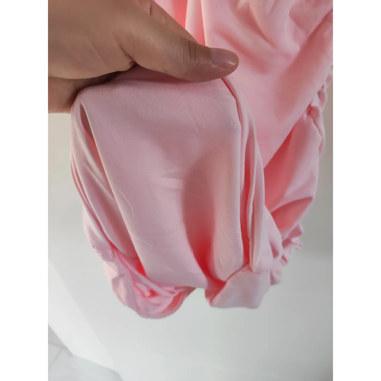 Hand‑held close‑up hem soft stretch fabric texture for pink ruched cami mini dress