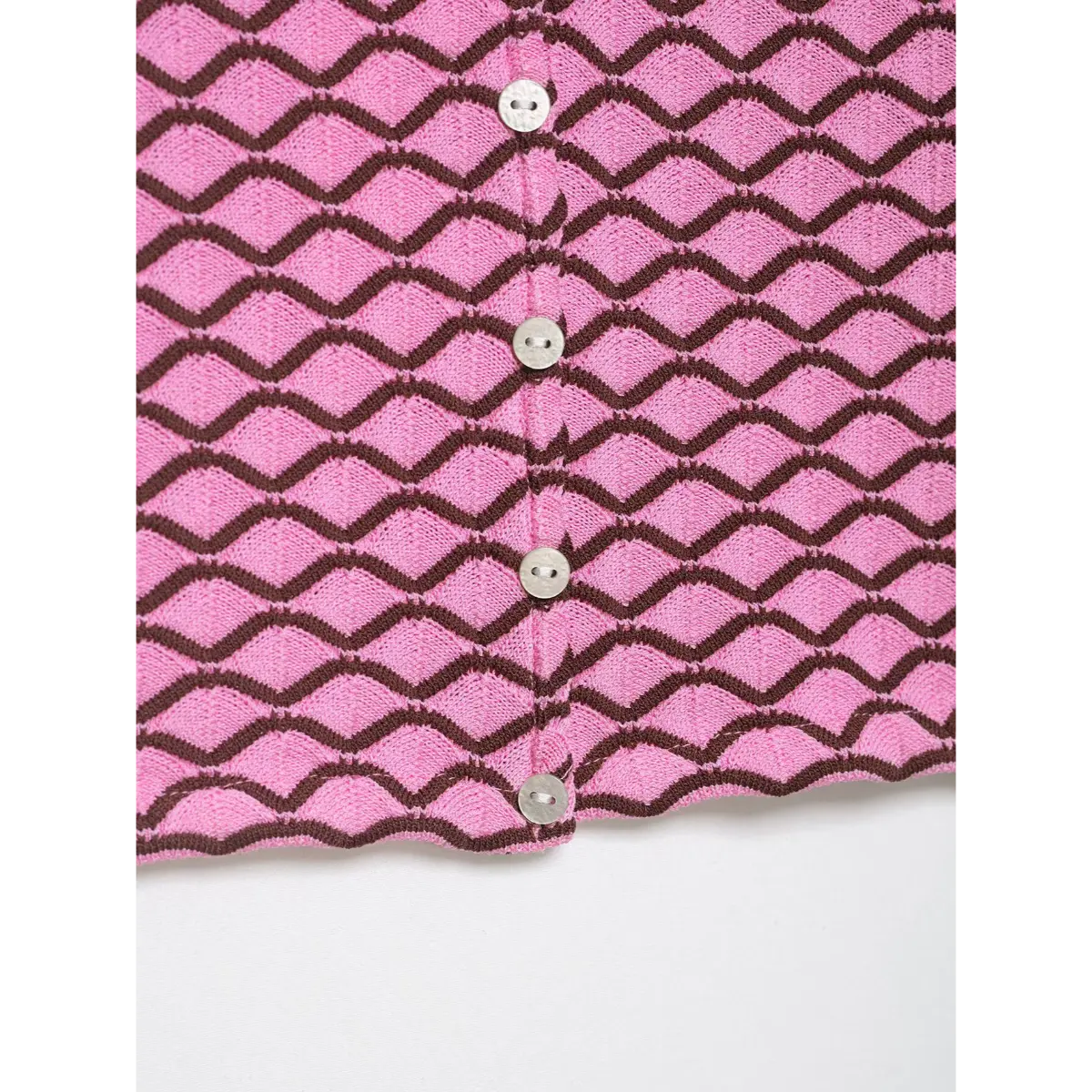 Close-up of pink and brown geometric knit cardigan, showing the mother-of-pearl buttons and fabric pattern