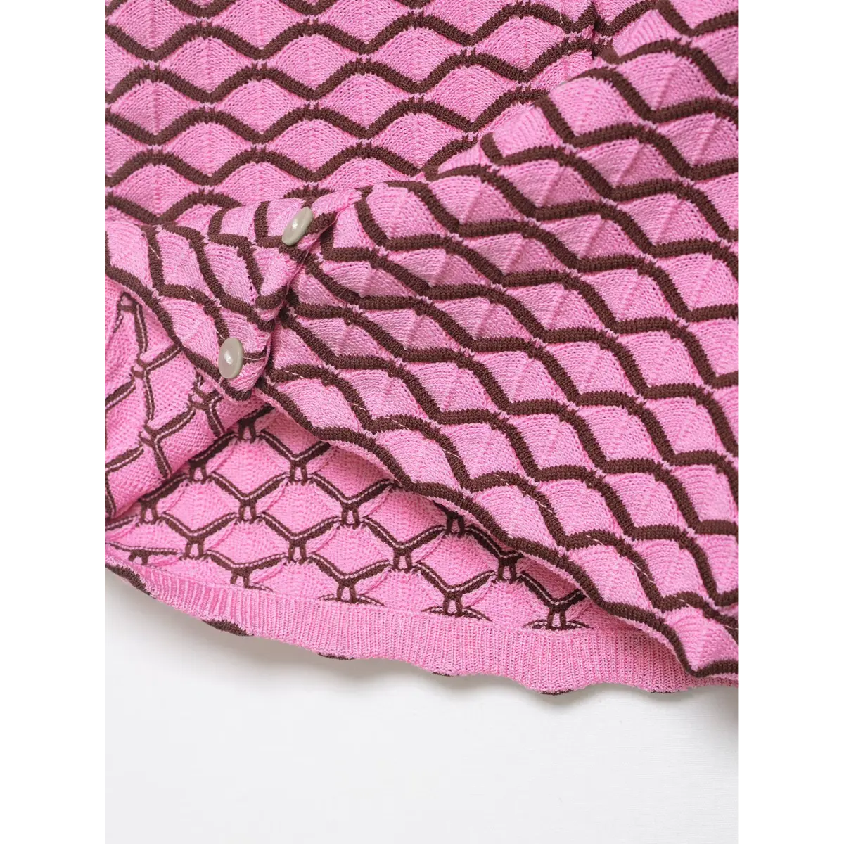 Interior view of pink and brown geometric knit cardigan, showing the lining and button attachment