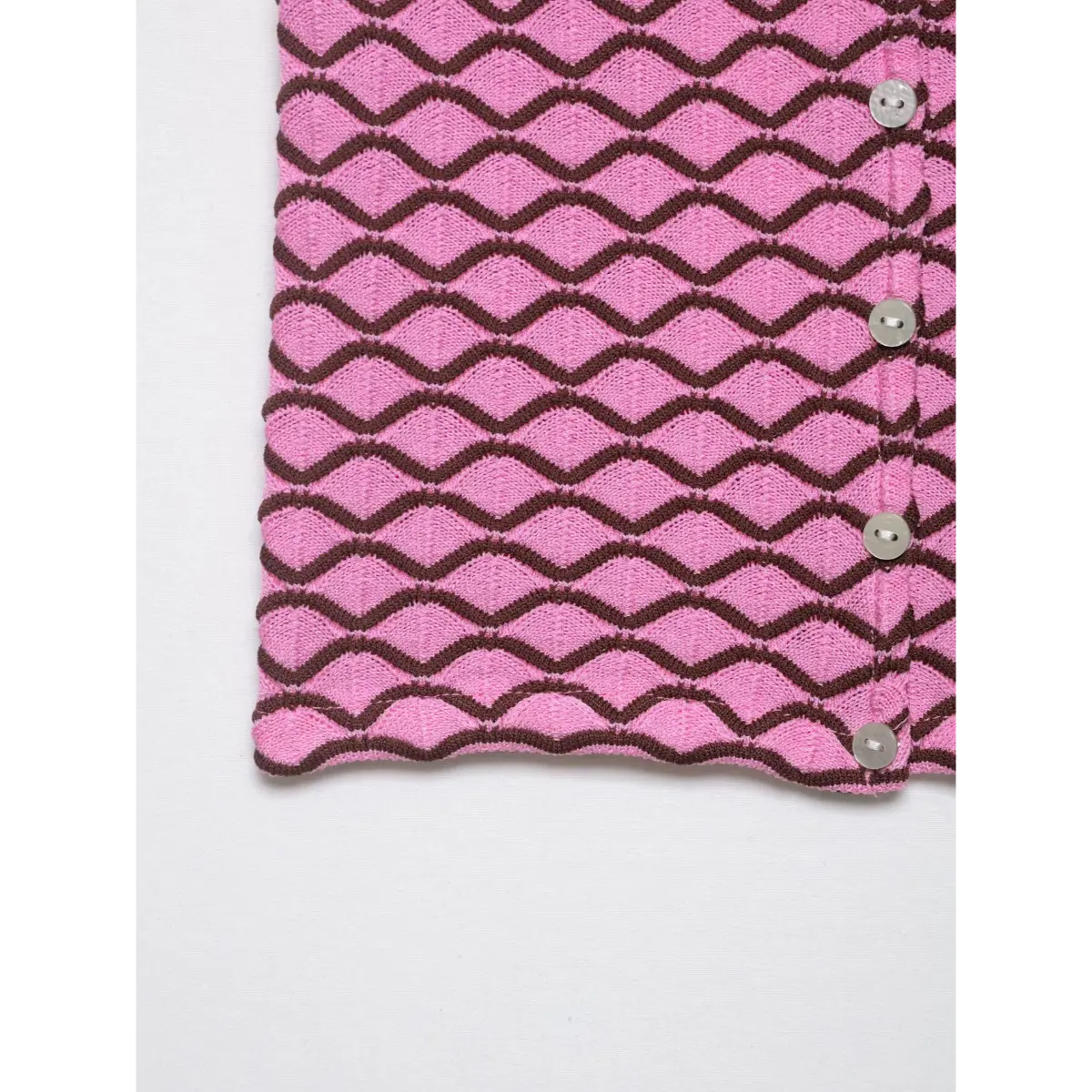 Side view of pink and brown geometric knit cardigan, highlighting the hem and repeating pattern