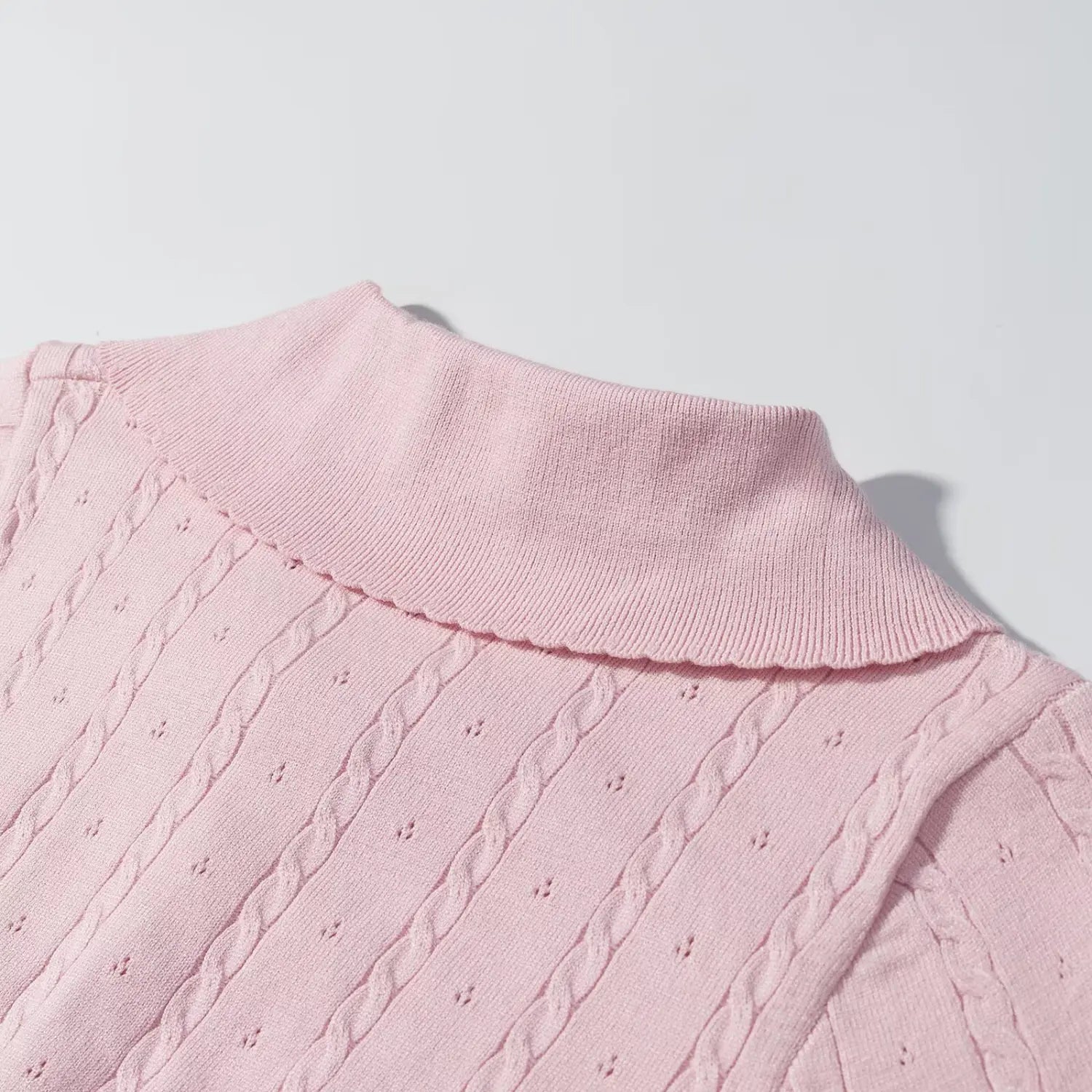 Close‑up back shoulder view of pink sweater scalloped peter pan collar, cable and eyelet knit pattern