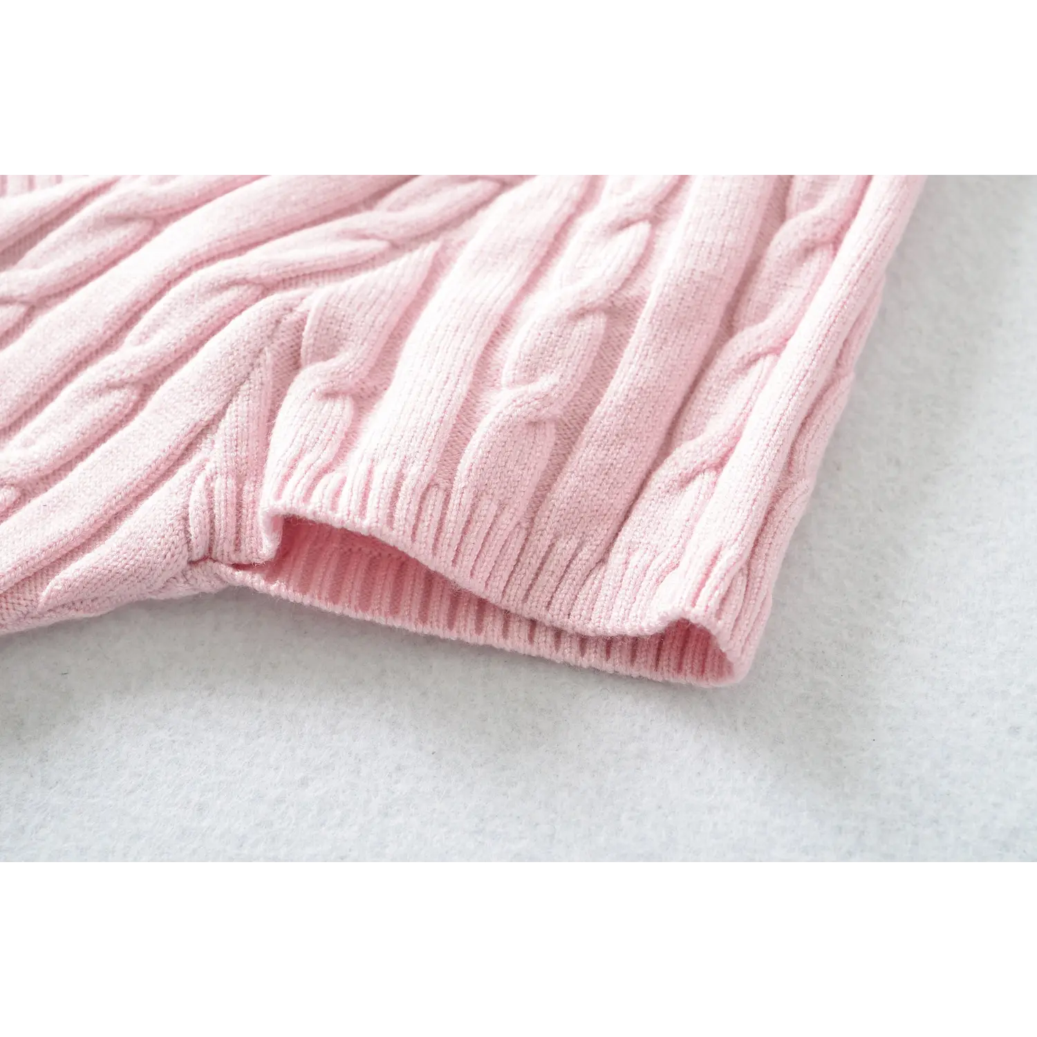 Macro close‑up of short sleeve ribbed cuff on pink cable knit sweater
