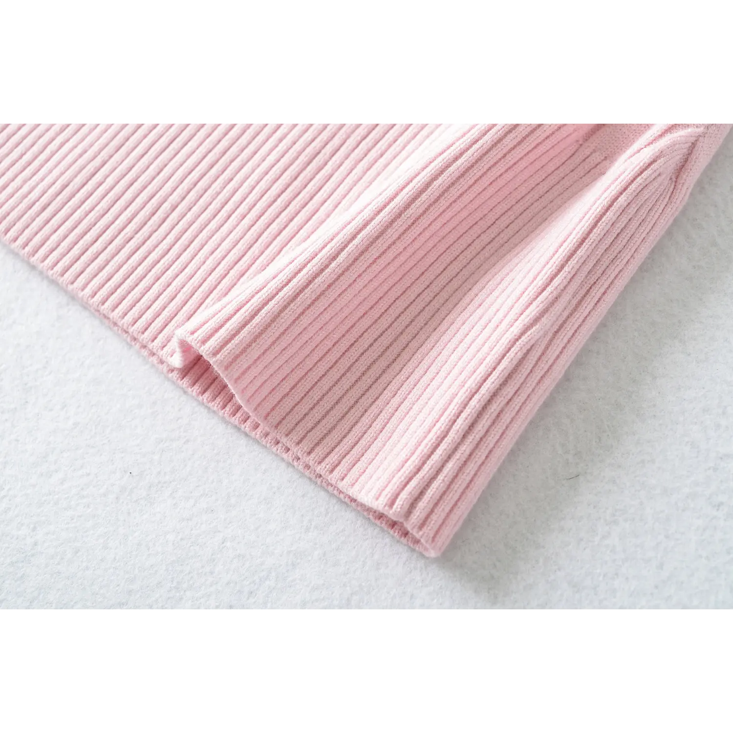 Detailed close‑up of ribbed sleeve hem stitching for pink knit top