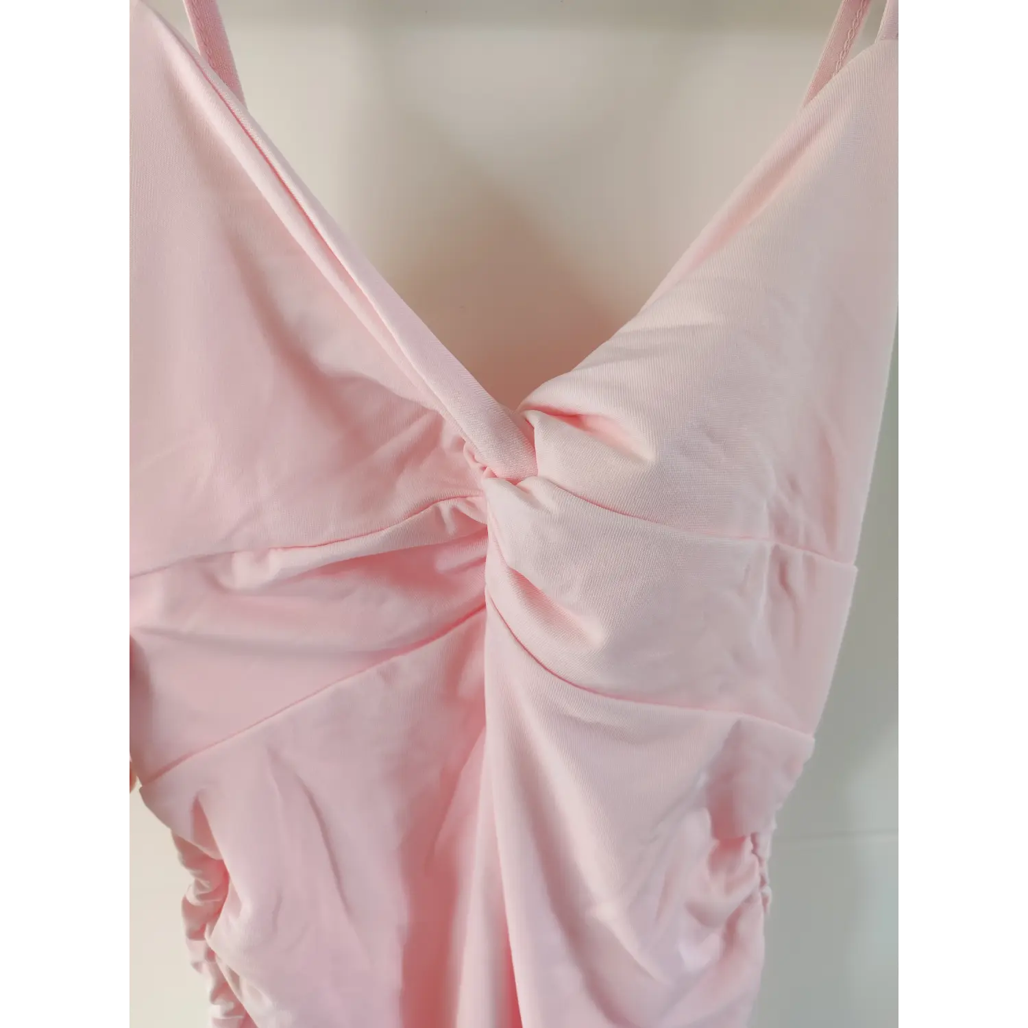 Extreme close‑up chest twist knot stitching detail of pink spaghetti strap bodycon dress