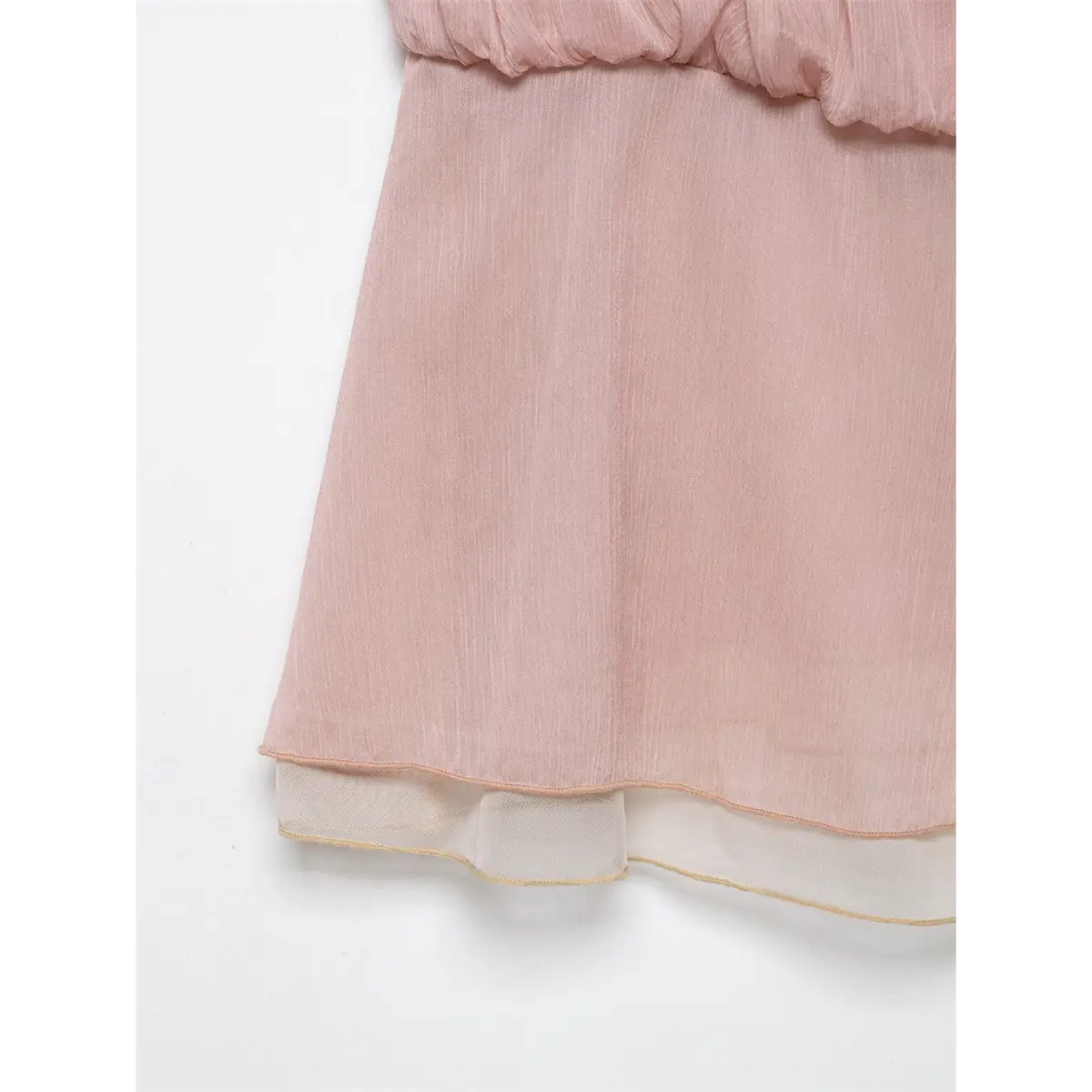 Close-up of the hem of a light pink cami top, showcasing the double-layered design, sheer lining, and soft, crinkled fabric texture.