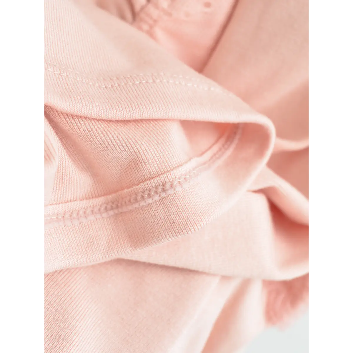 Close-up of the fabric hem on pink cami top, showing fine stitching and smooth knit texture.