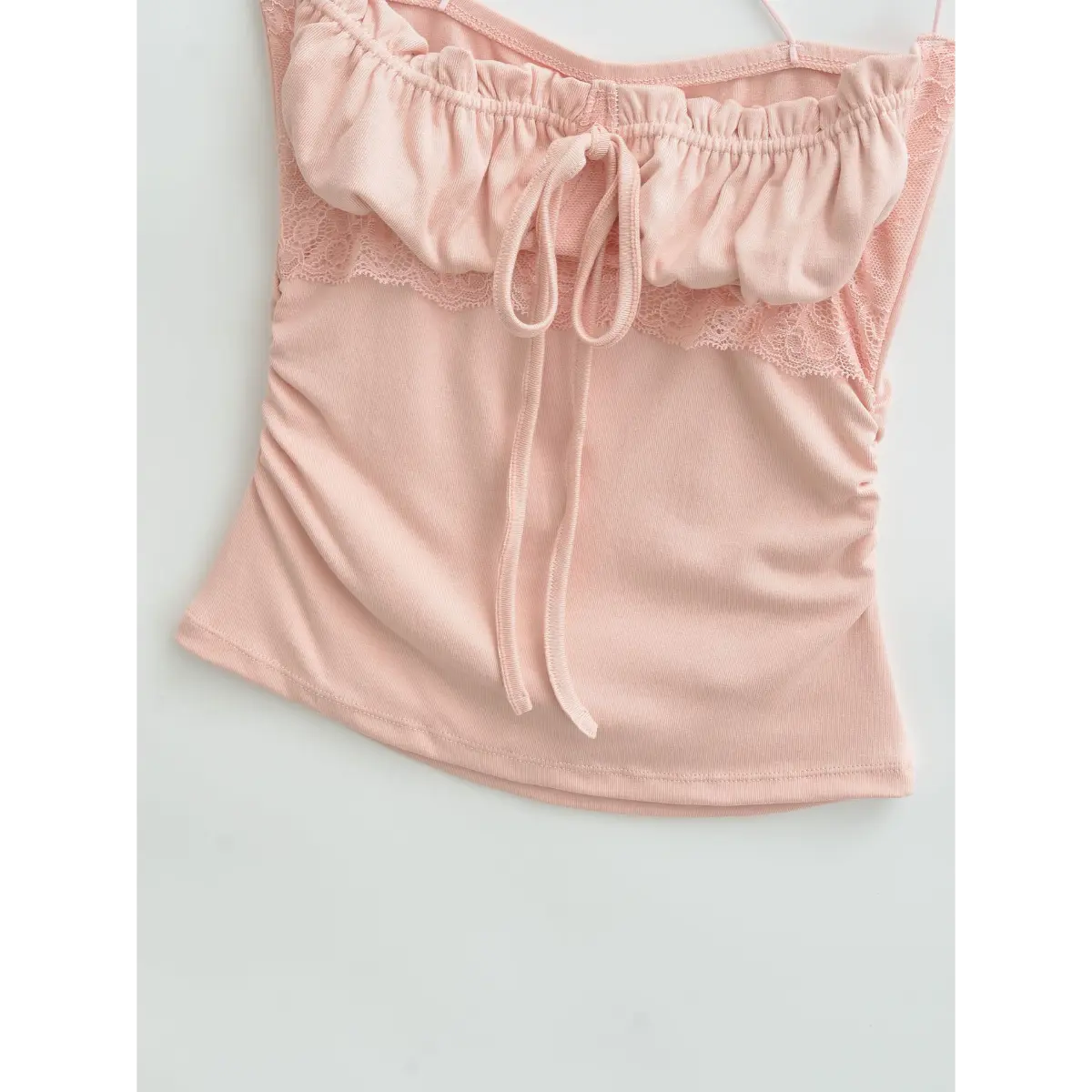 Close-up of the bottom hem on pink cami top, showing finished stitching and ruched side details.
