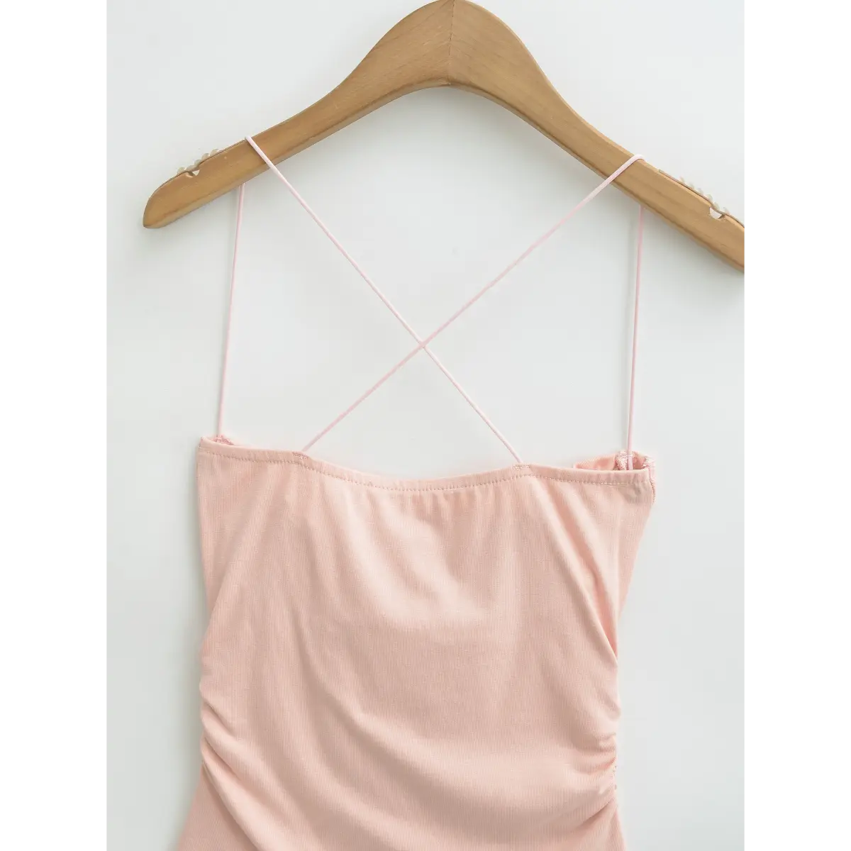 View of the crisscross straps on pink cami top, showing thin elastic straps and clean neckline.