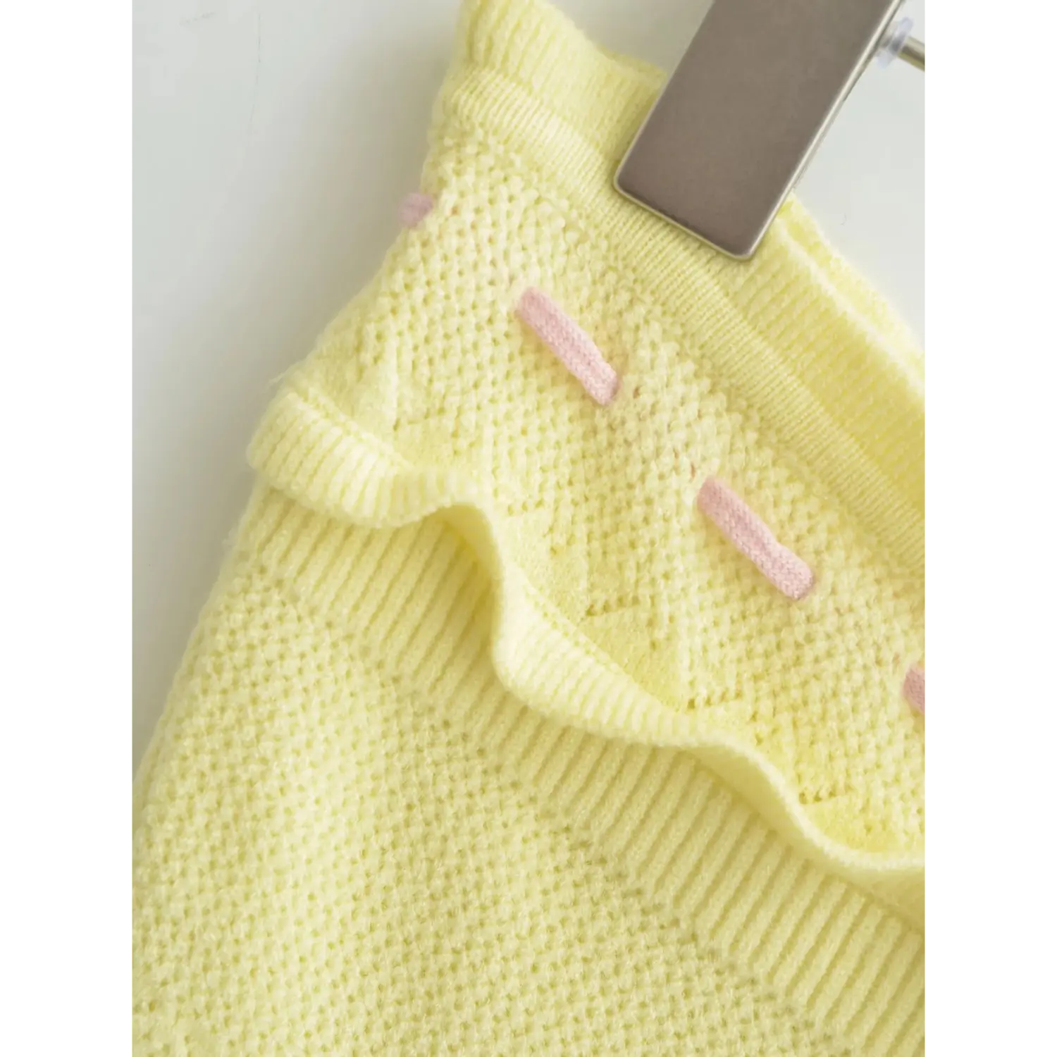 Closeup horizontal pink bar tacks along scalloped top ruffle