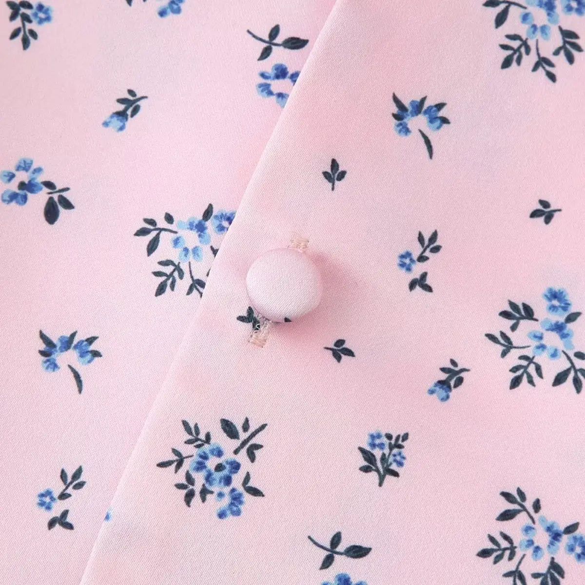 Close-up of the fabric-covered button on the pink ditsy floral blouse, matching the pink print
