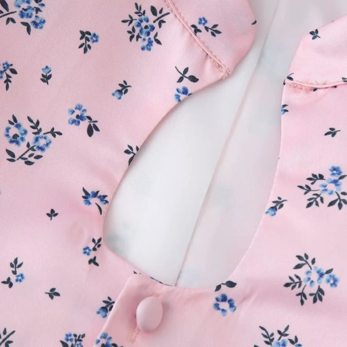 Close-up of the keyhole cutout on the pink ditsy floral blouse, showing the fabric-covered button and smooth lining