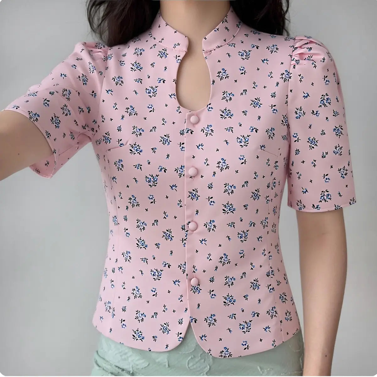 The pink ditsy floral blouse worn by a model, showing the fitted silhouette, keyhole neckline, and puff sleeves