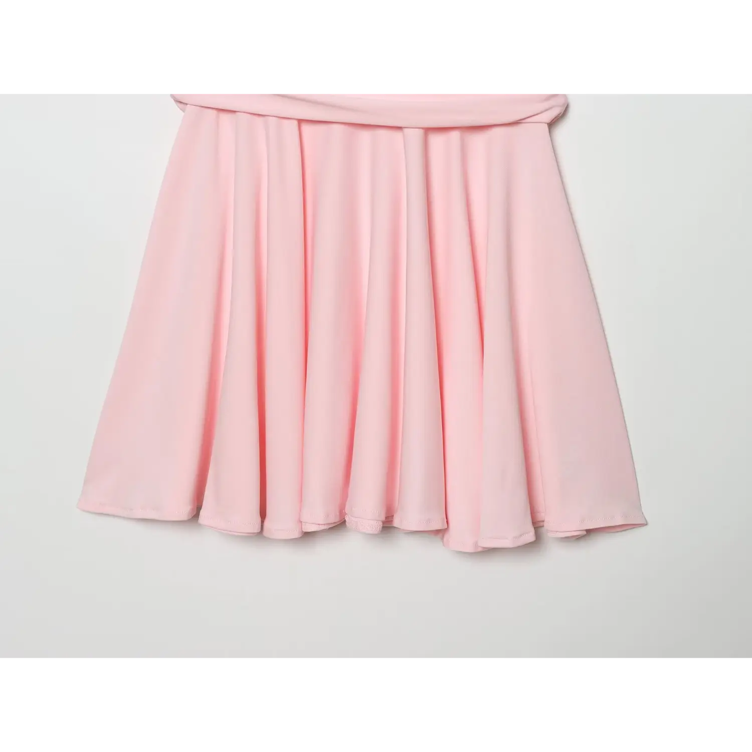 Close-up of flowy pleated skater skirt hem on light pink mini dress, neat finished edge