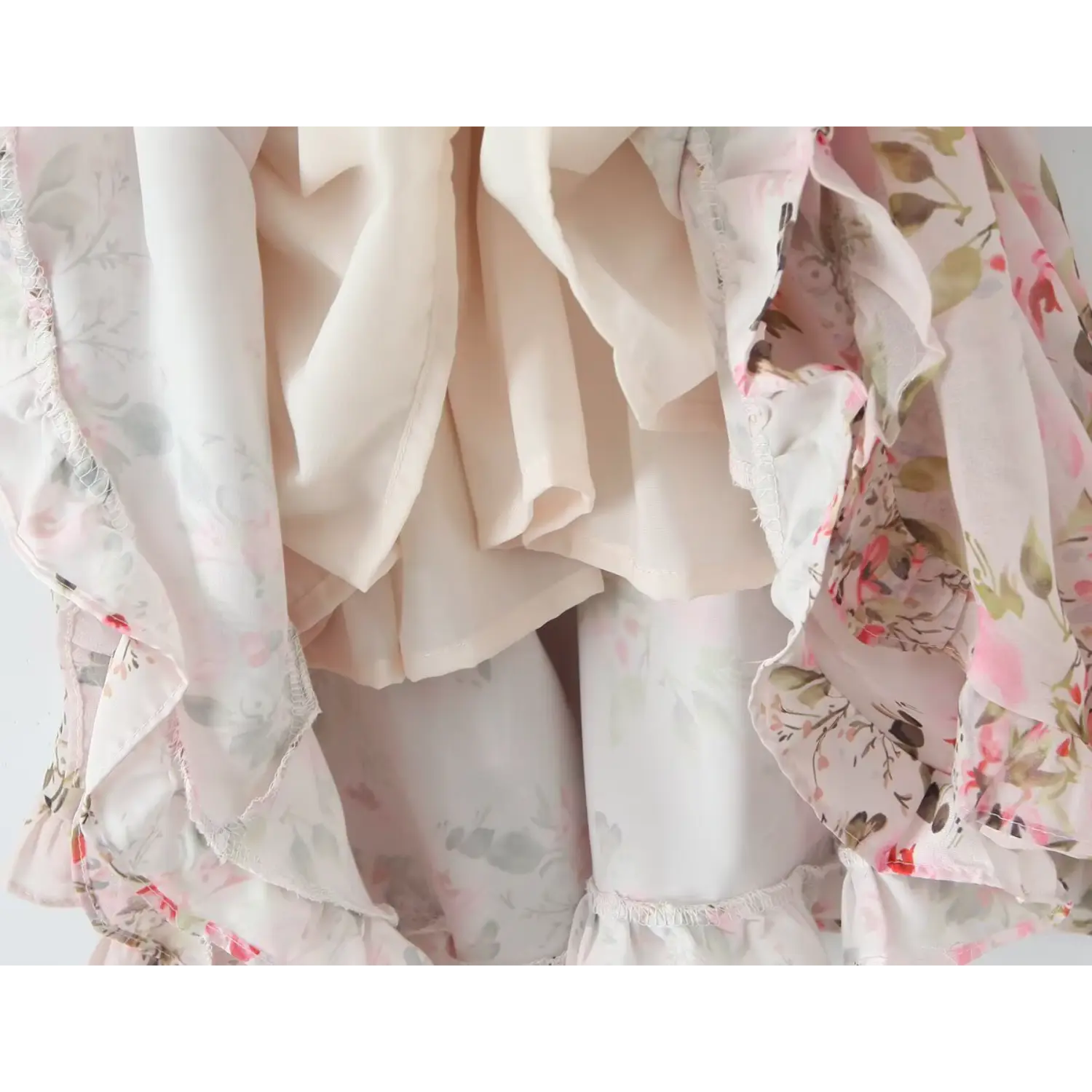 Inner lining close‑up of pink floral chiffon mini dress, layered ruffle hem construction