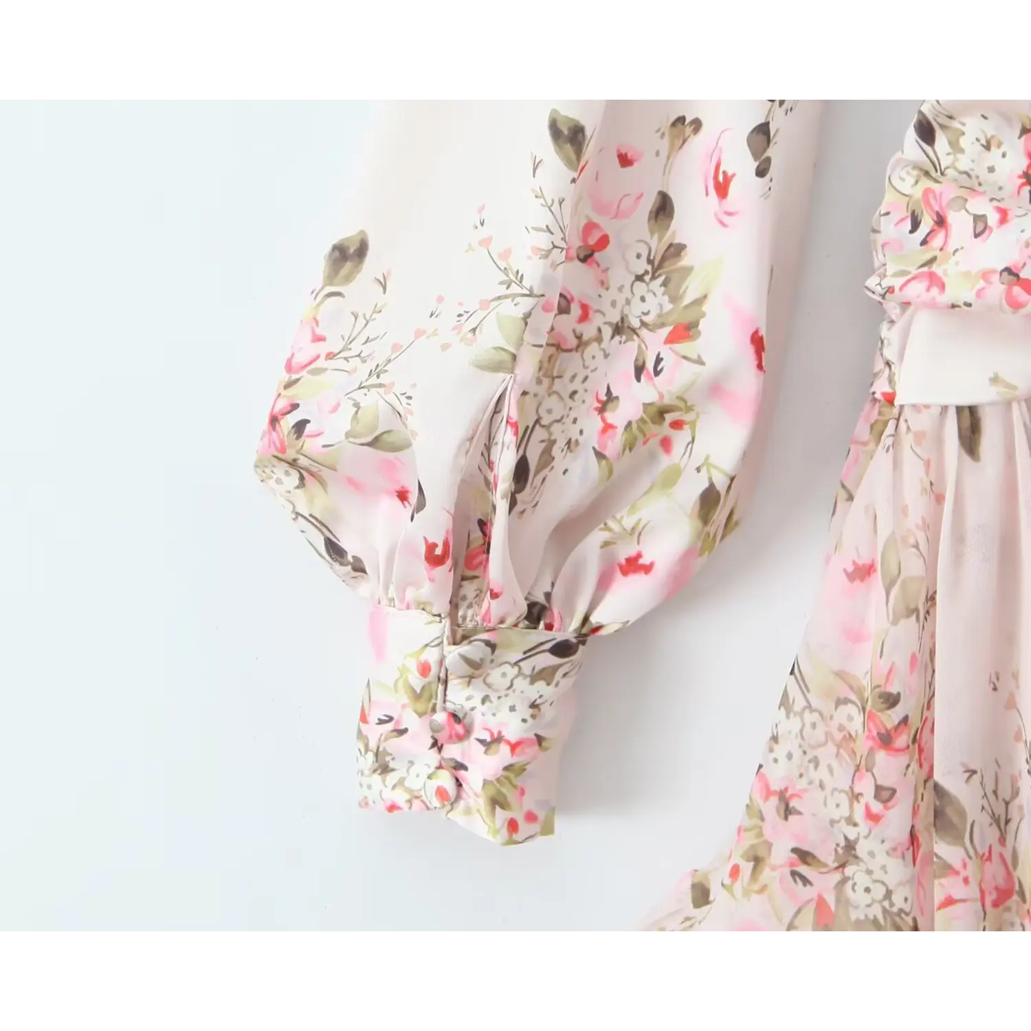 Close‑up of balloon sleeve cuff with covered button on pink floral chiffon mini dress