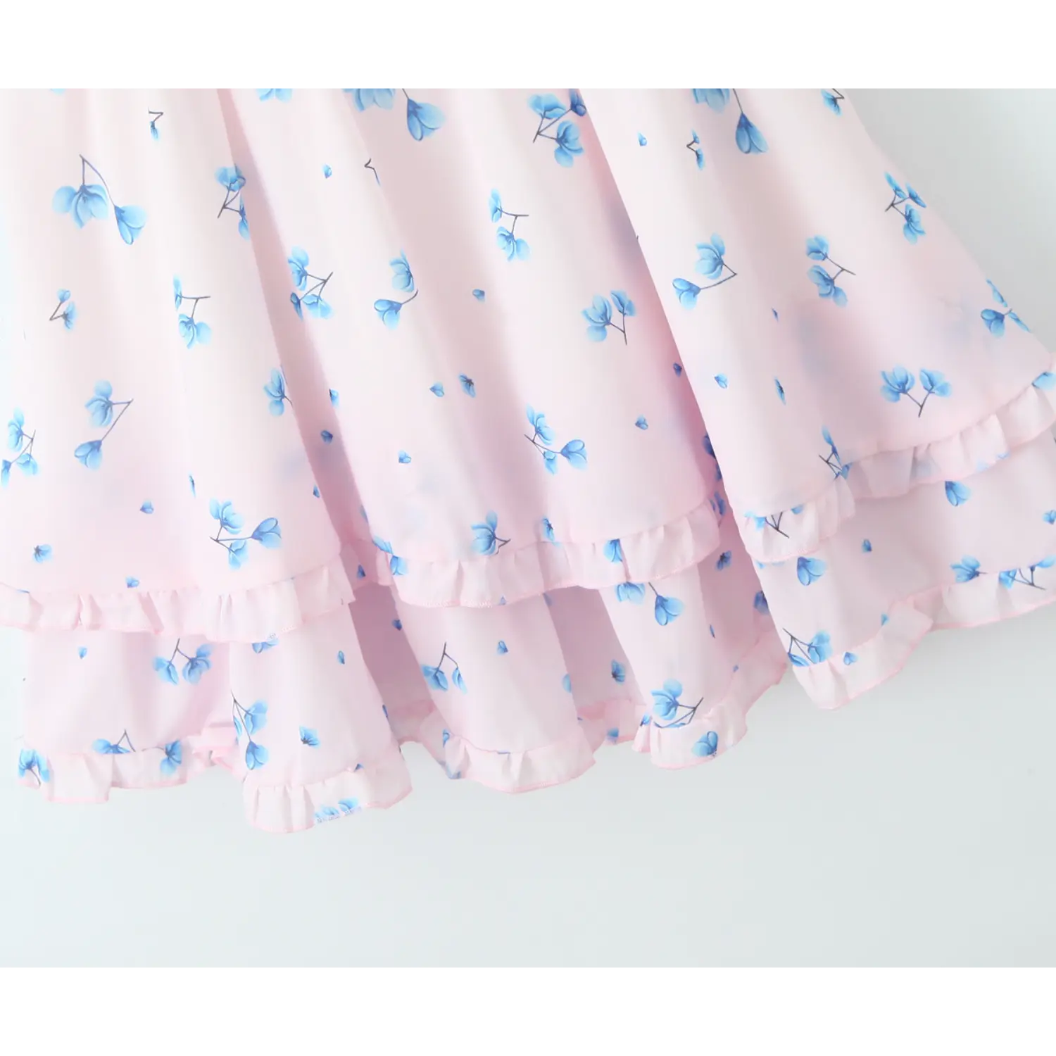 Close‑up double layer tiered ruffle skirt hem, frilled edge trim, flowy chiffon fabric, all‑over blue floral print