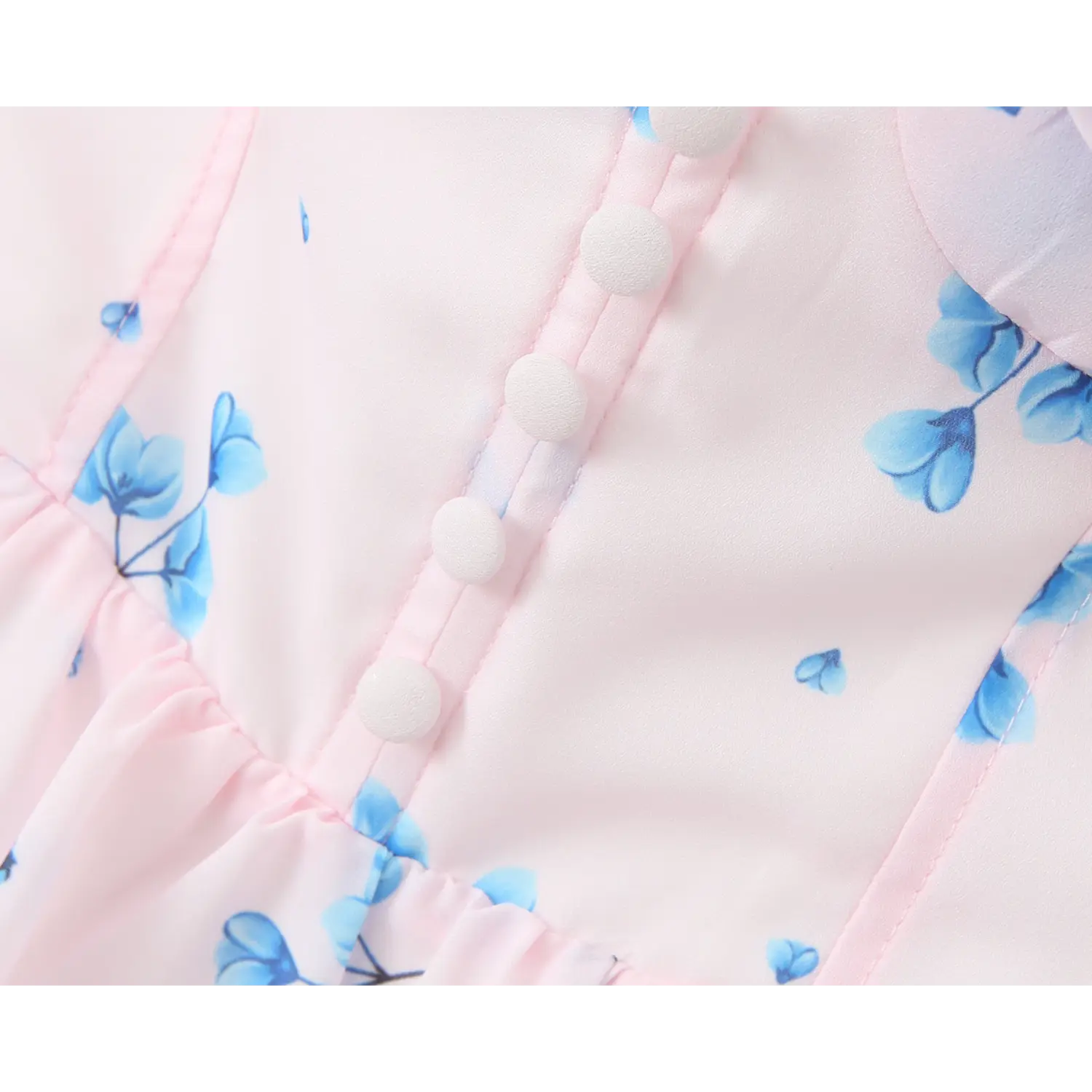 Close‑up of bodice front decorative covered buttons, fine stitching, pale pink fabric with blue floral print