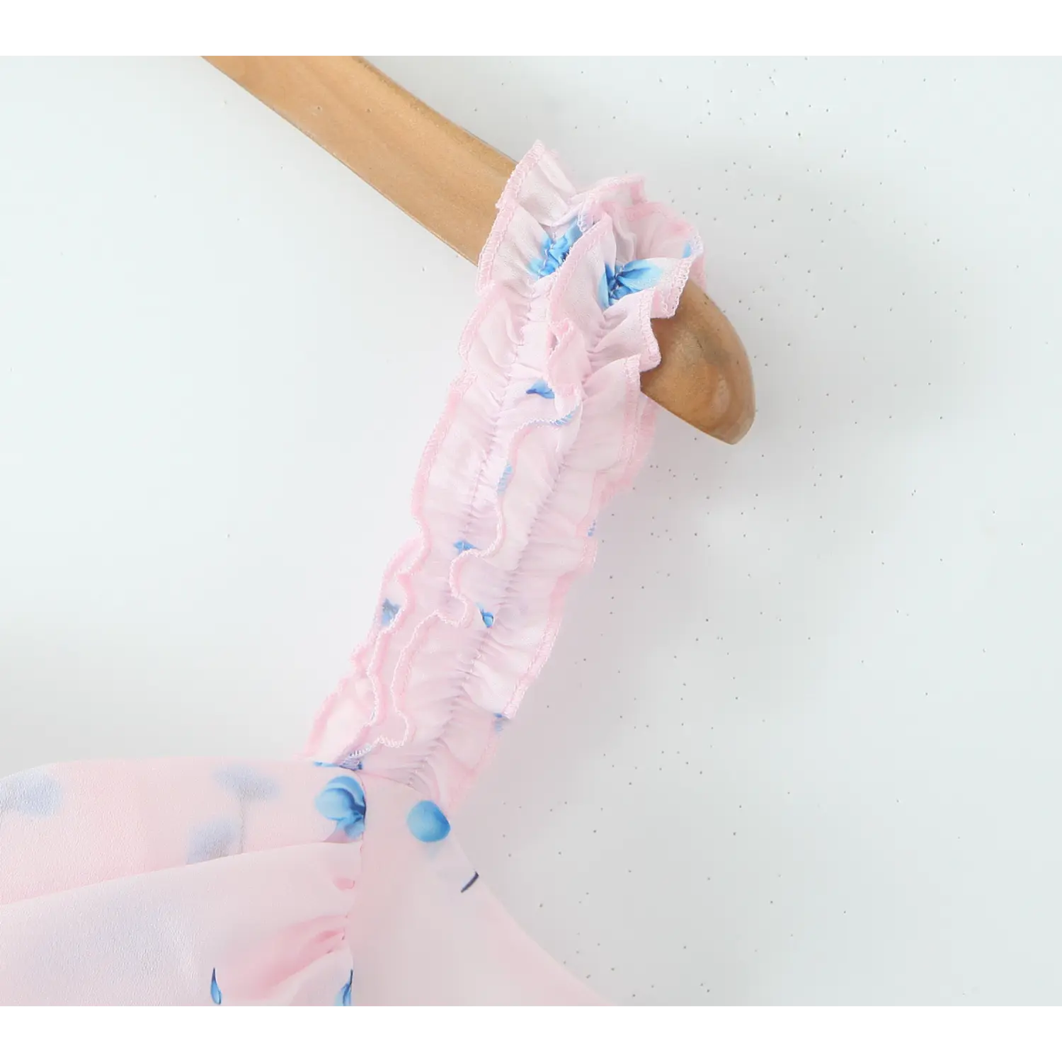 Macro close‑up of elastic ruffle shoulder strap, smocked gathered ruffle trim, pink base with scattered blue floral print