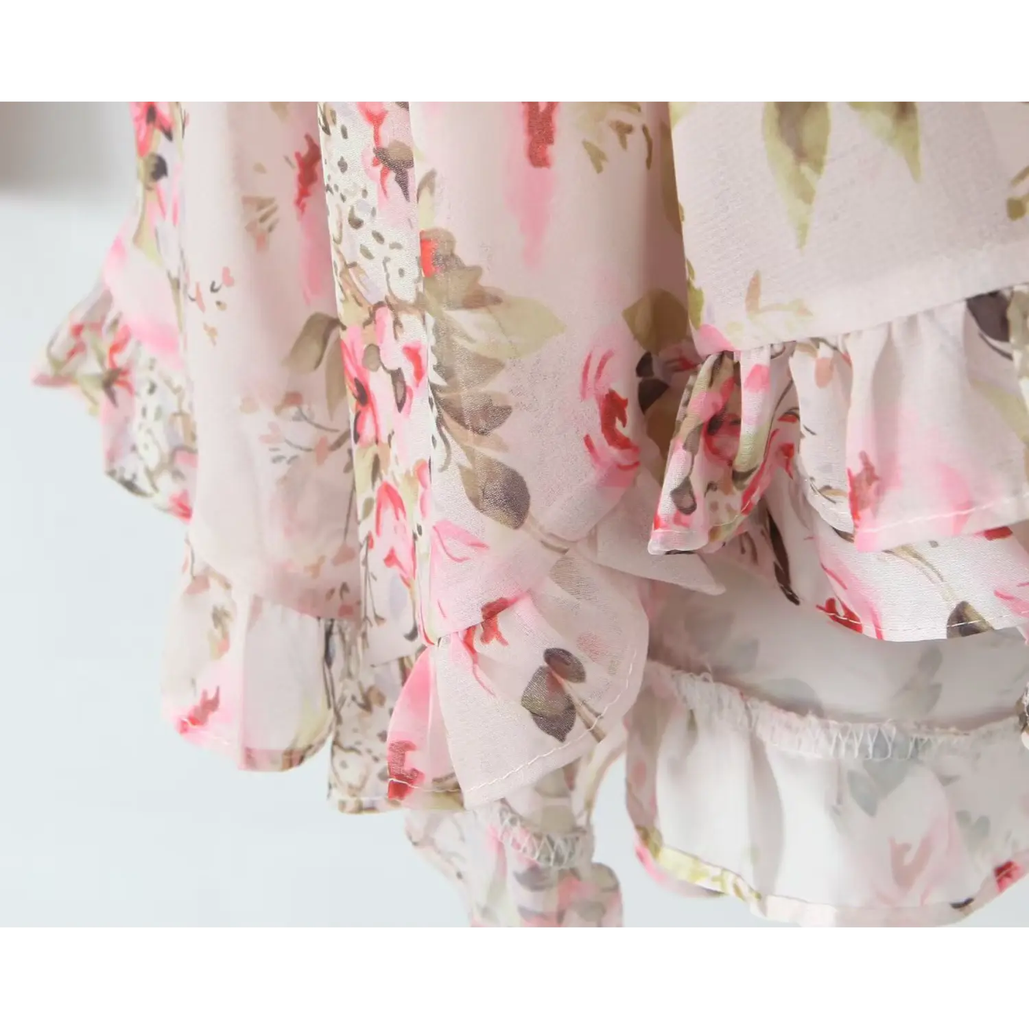 Close‑up tiered ruffle hem of pink floral chiffon mini dress, flowy layered chiffon trim