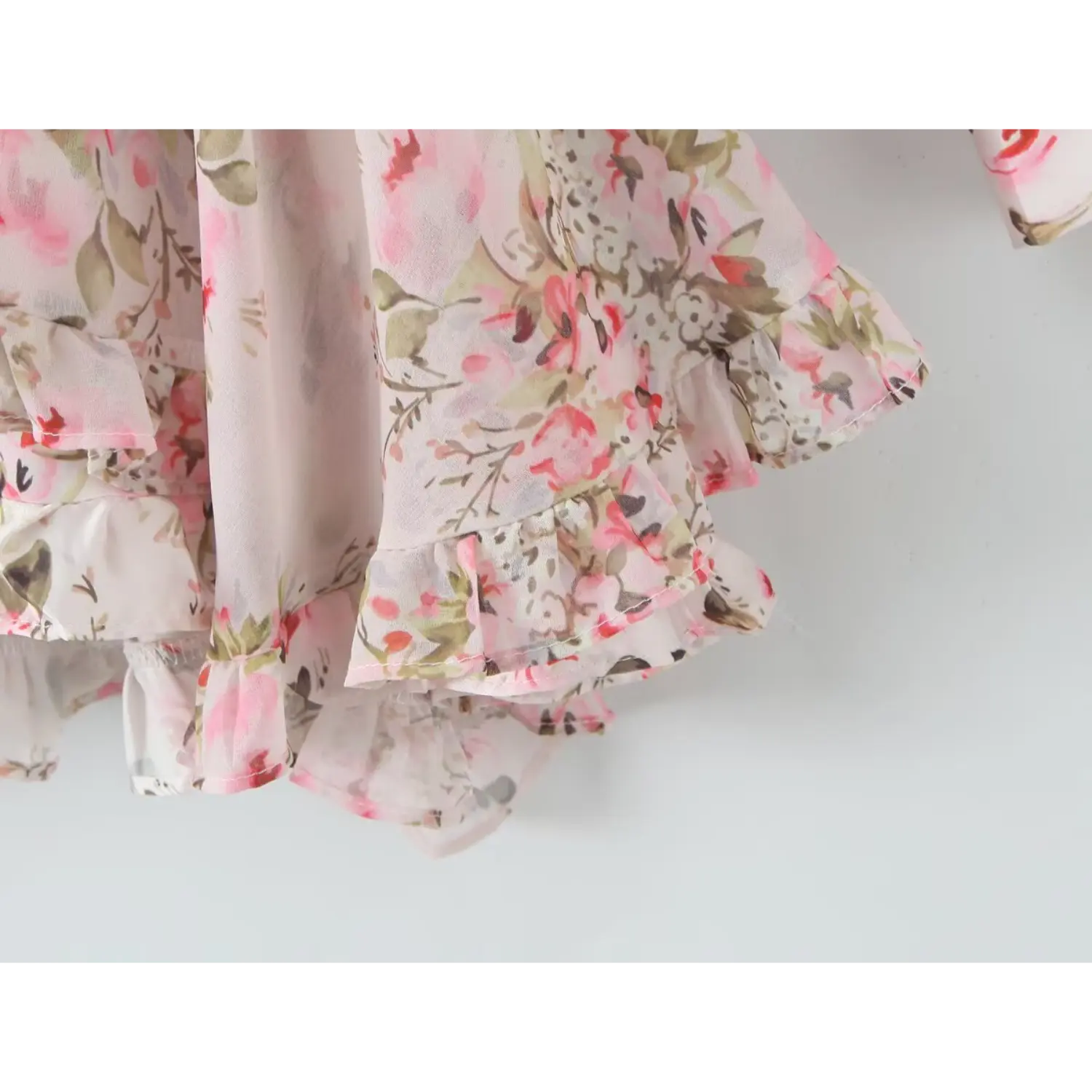 Close‑up layered ruffle skirt hem of pink floral chiffon mini dress