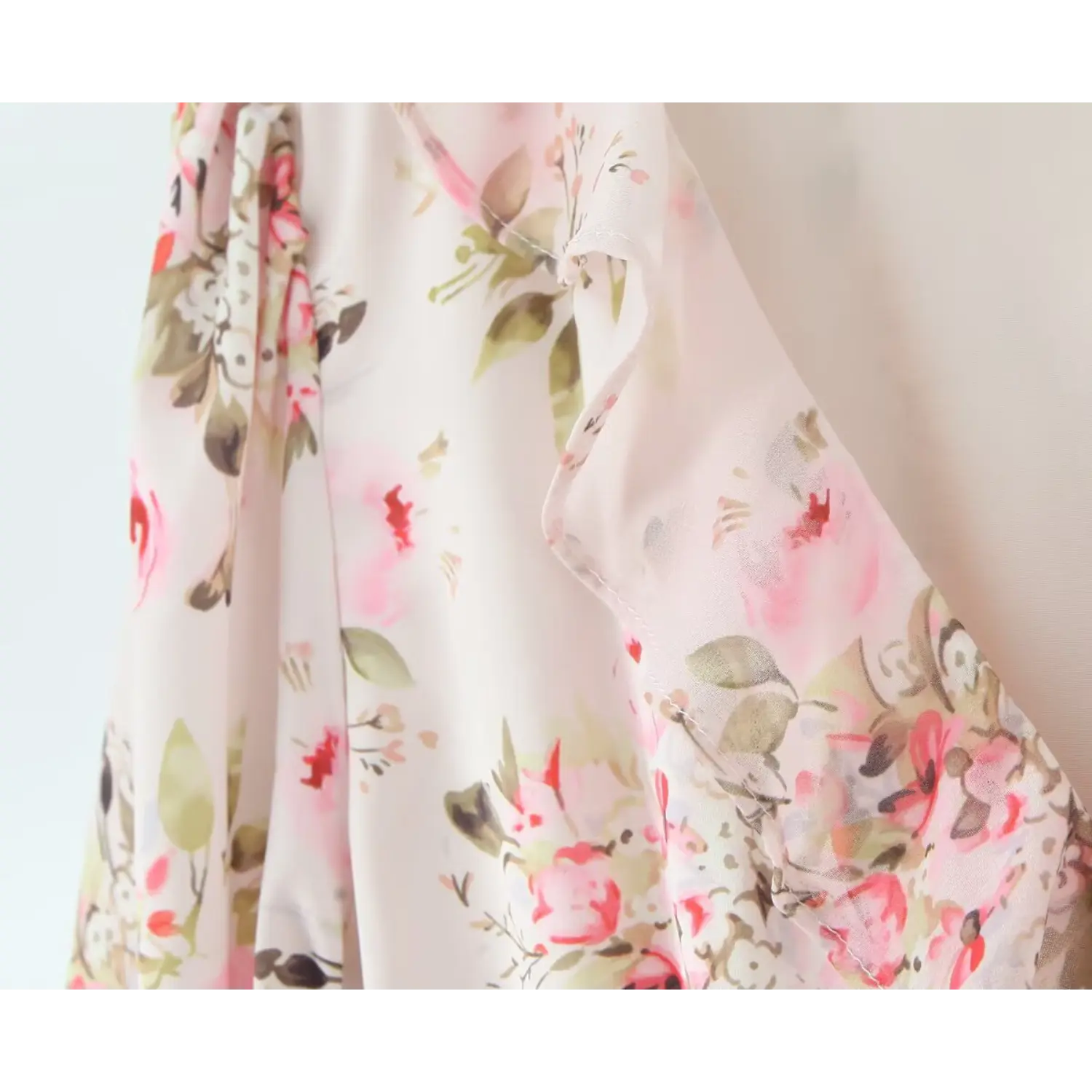 Close‑up of v‑neck ruffle edge detail on pink floral chiffon mini dress