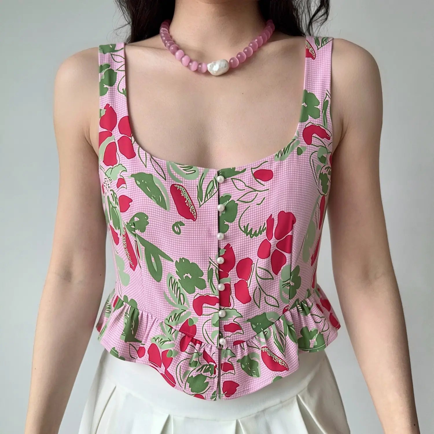 Model wearing pink floral fruit print sleeveless ruffle hem crop top