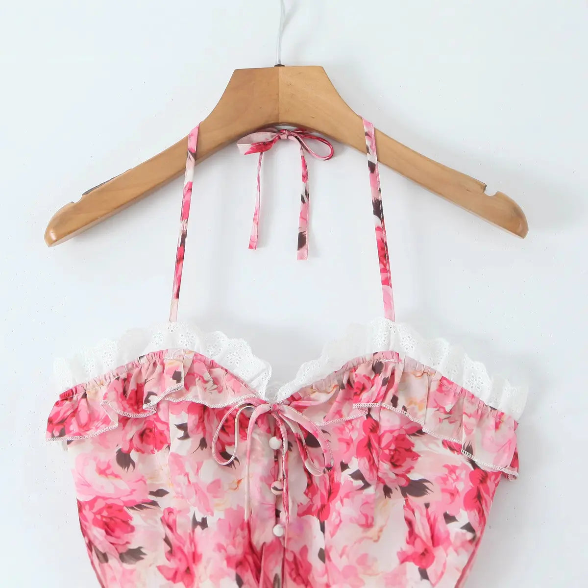 Front view of the pink floral halter corset top on a wooden hanger.