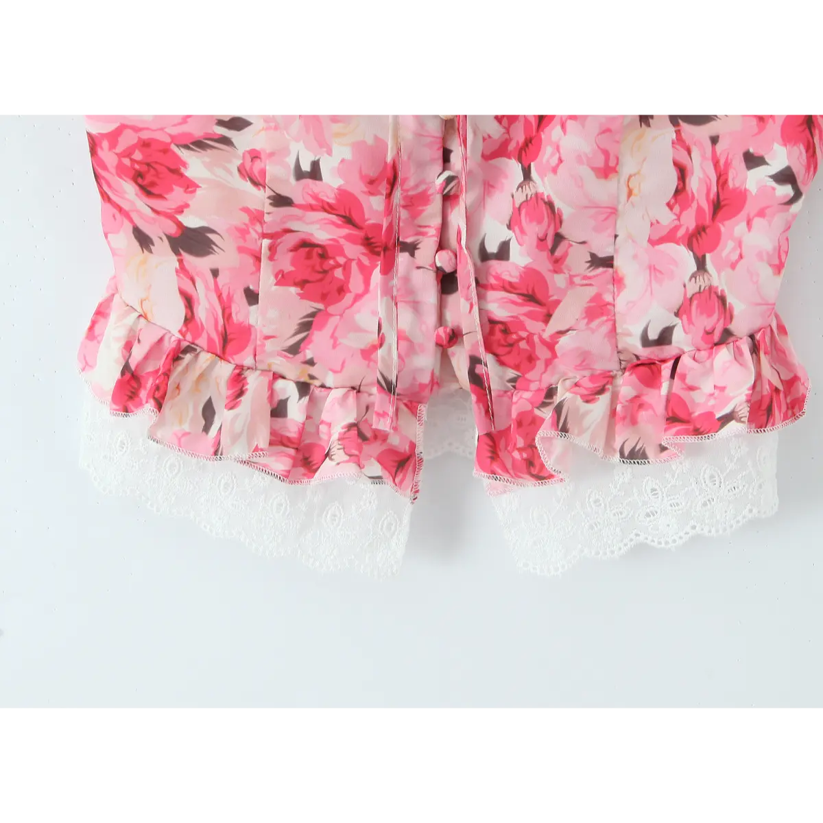 Close-up of the white lace-trimmed hem and floral print on the pink corset top.