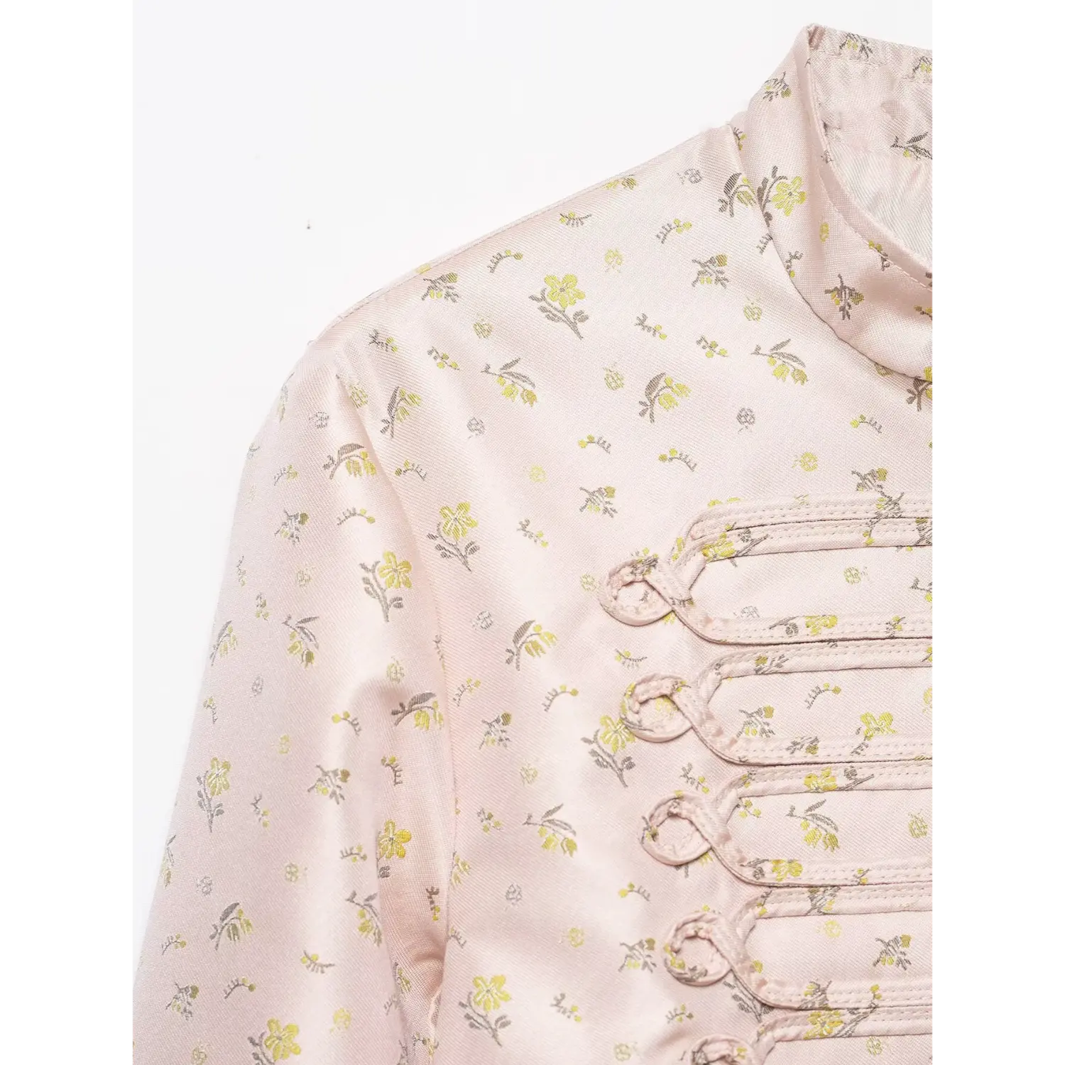 Close-up shoulder fabric and decorative loop detail, pink ditsy yellow floral satin cropped coat