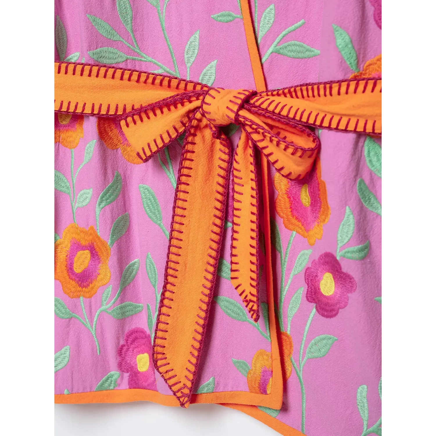Close up of orange stitched belt bow on pink floral embroidered wrap jacket