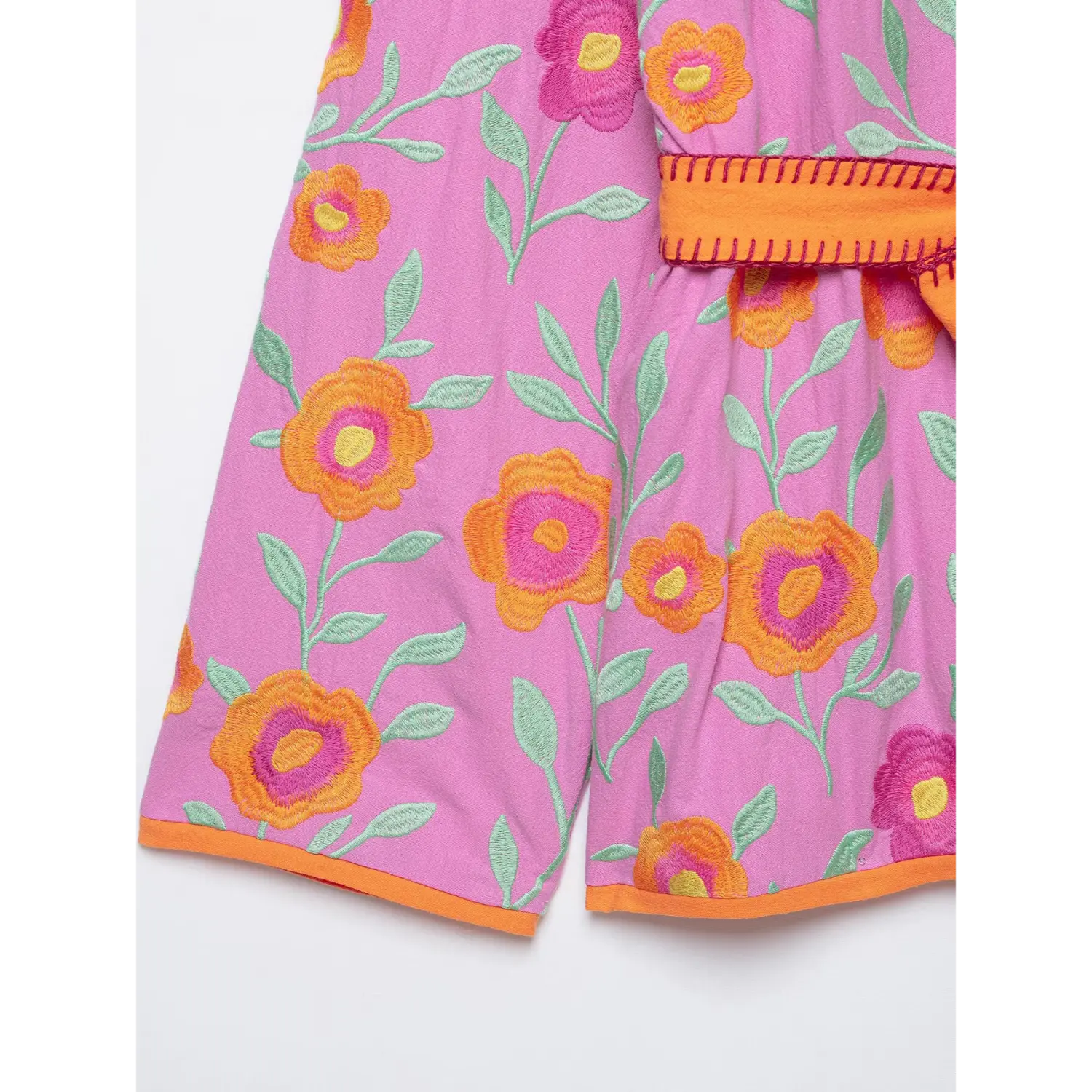 Close view of flower embroidery and orange hem trim on pink wrap kimono jacket