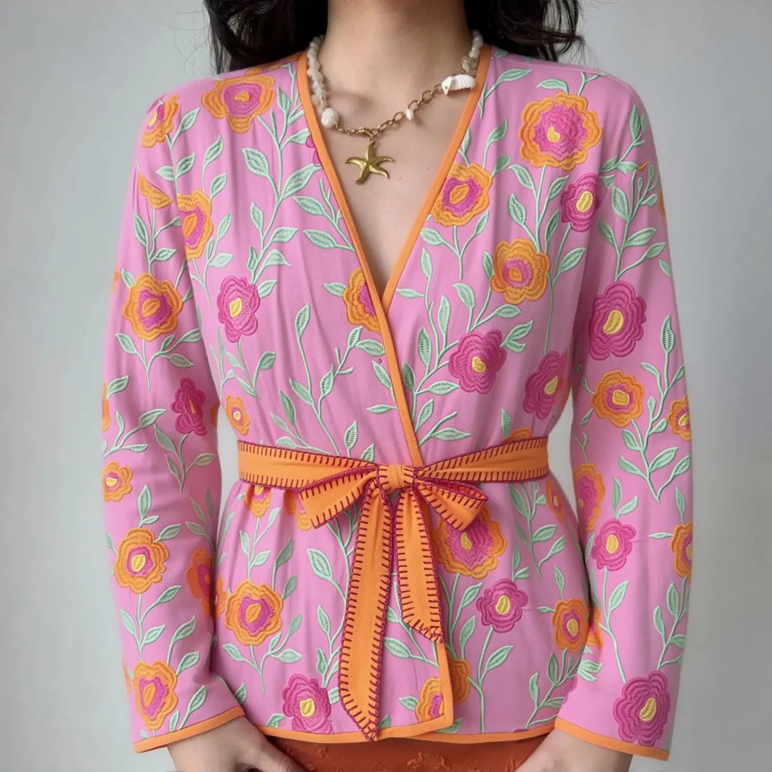 Female model wearing pink floral embroidery V-neck wrap kimono jacket with orange tie belt