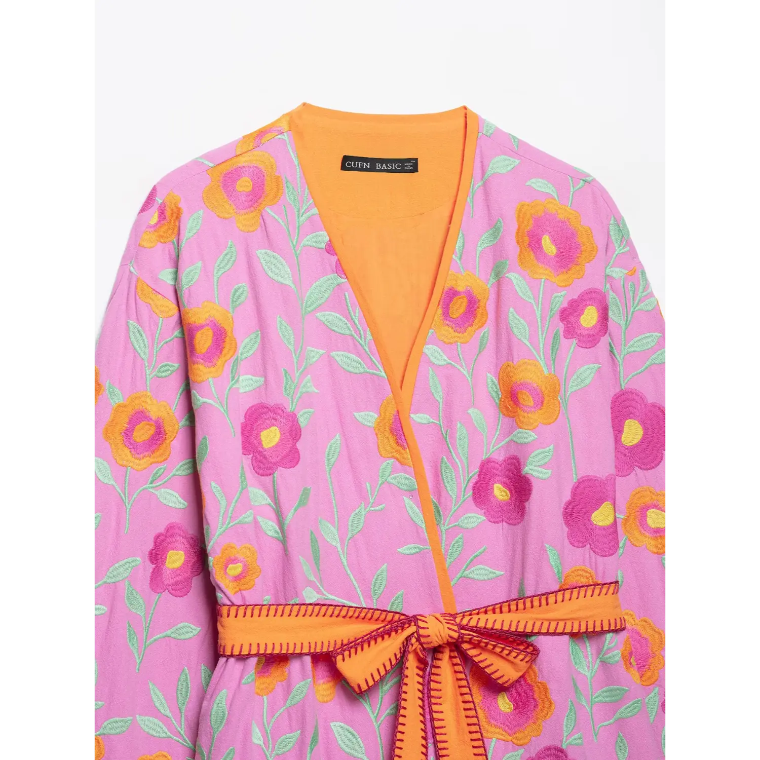 V-neck detail of pink floral embroidered wrap jacket, orange inner lining and stitched belt