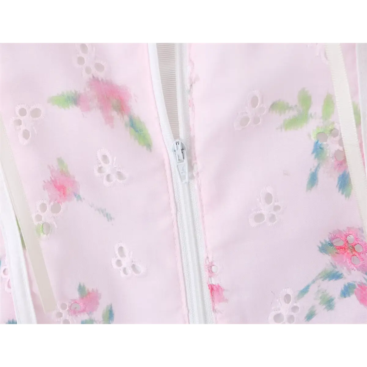 Close-up of the delicate floral print and eyelet fabric texture on the pink cami top