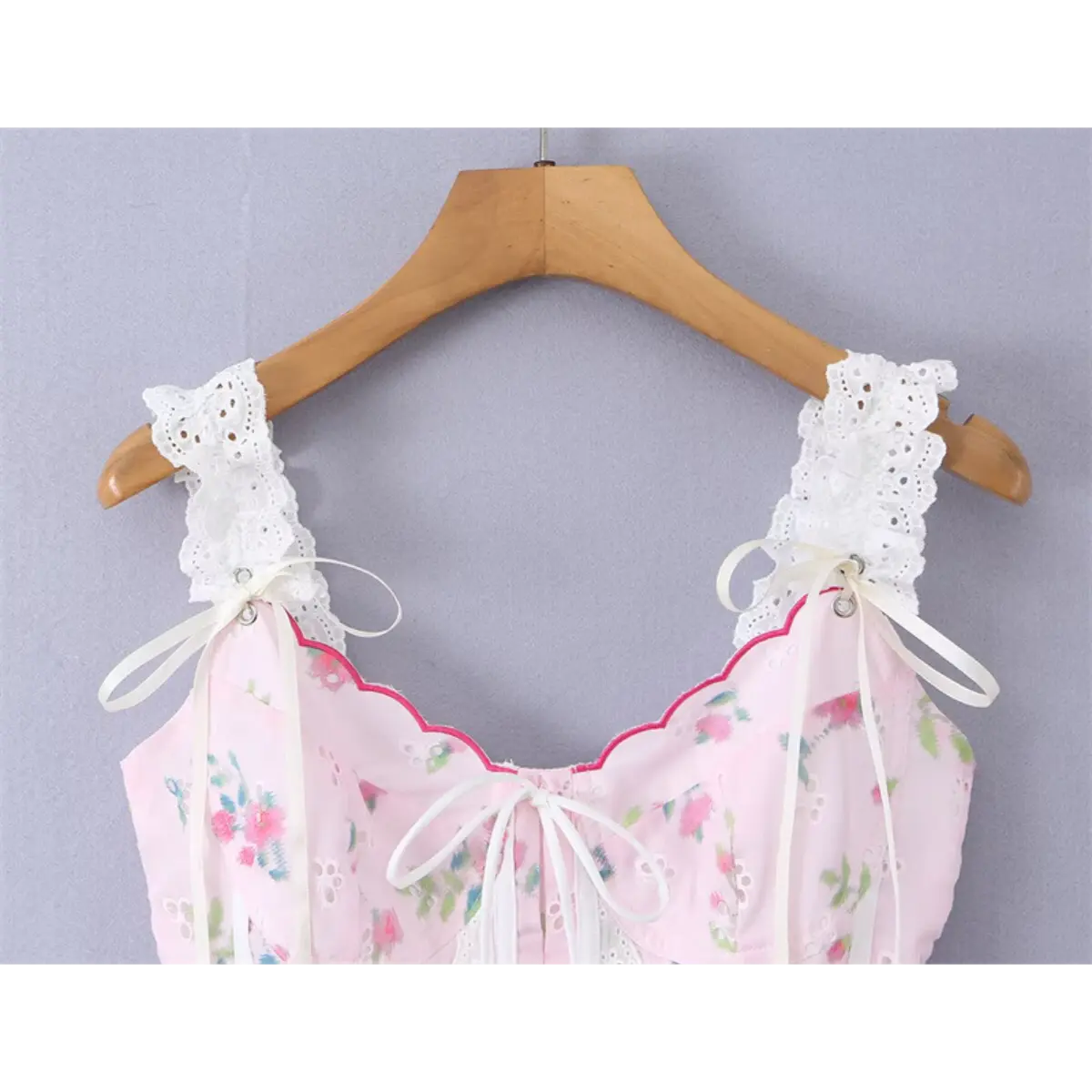 Close-up view of the pink floral cami top hanging on wooden hanger, focusing on front bow and lace straps