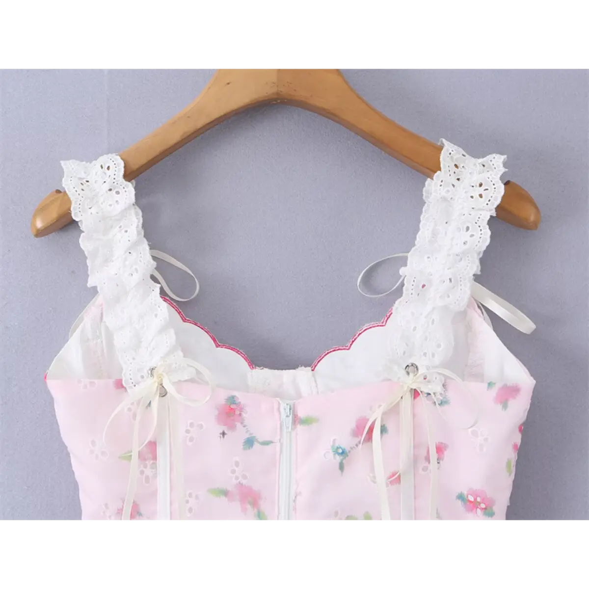 Close-up view of the pink floral cami top hanging on wooden hanger, focusing on the scalloped neckline