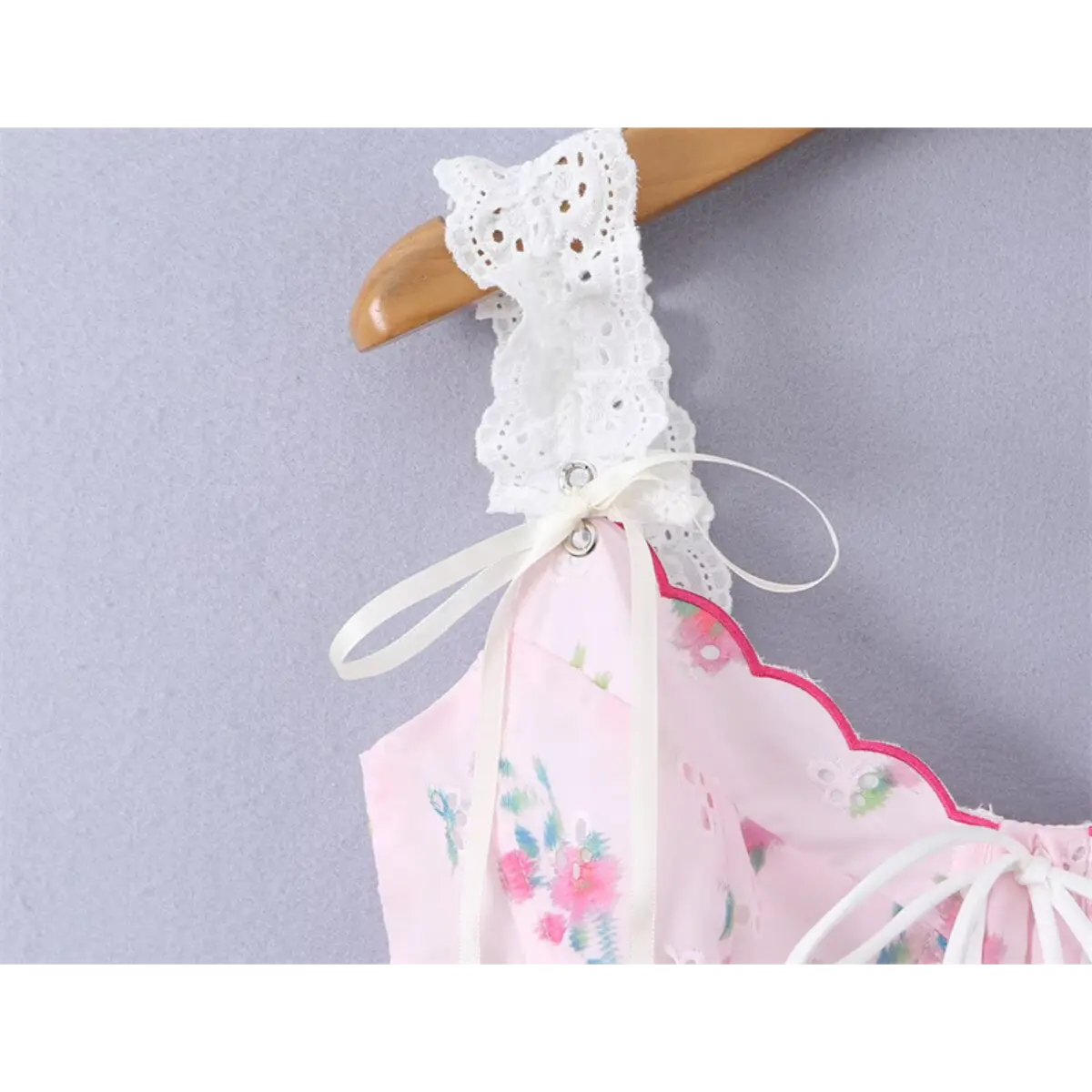 Close-up of the ruffled lace straps and ribbon ties on the pink floral cami top
