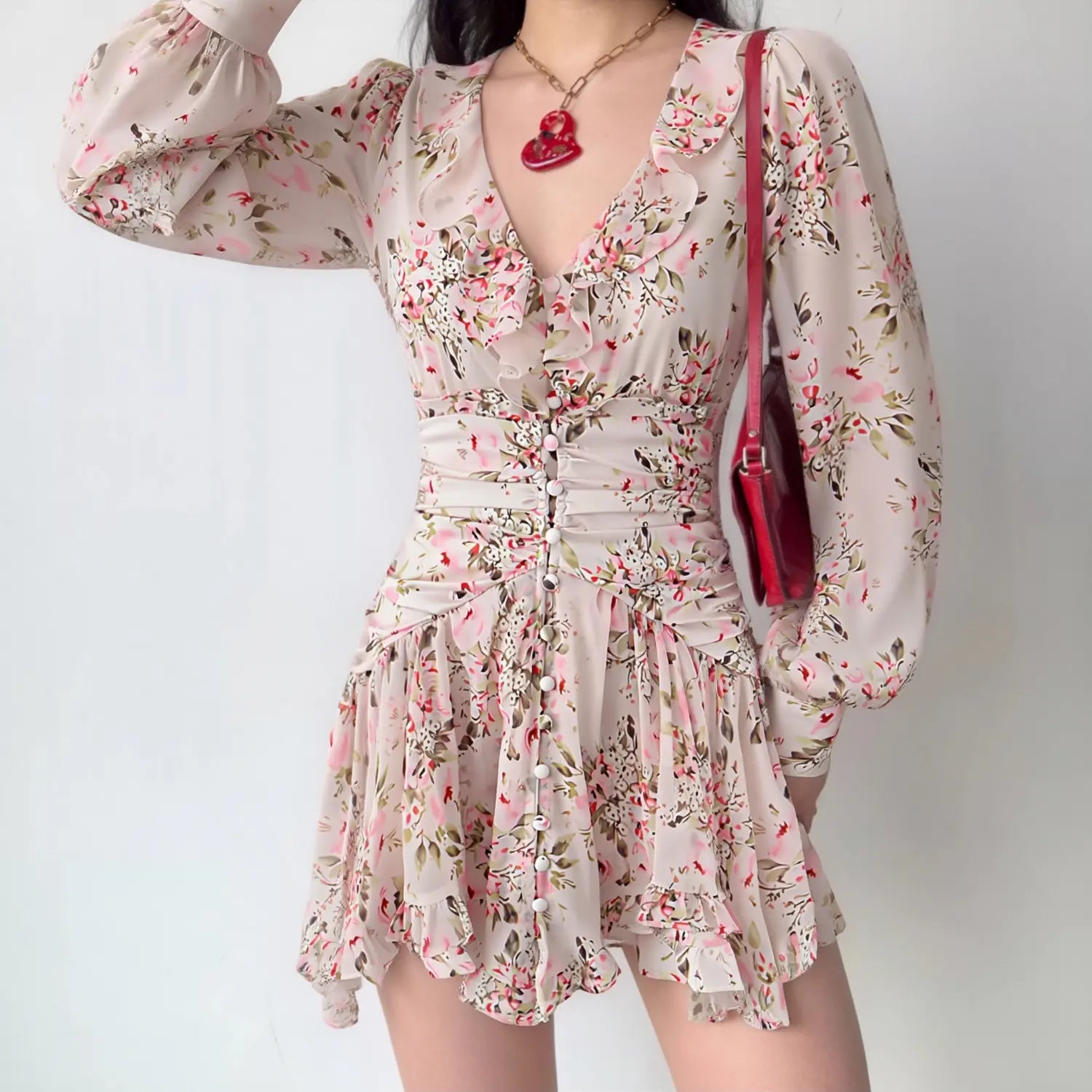 Model wearing pink floral long sleeve mini dress, v‑neck ruffle, ruched waist, tiered ruffle skirt