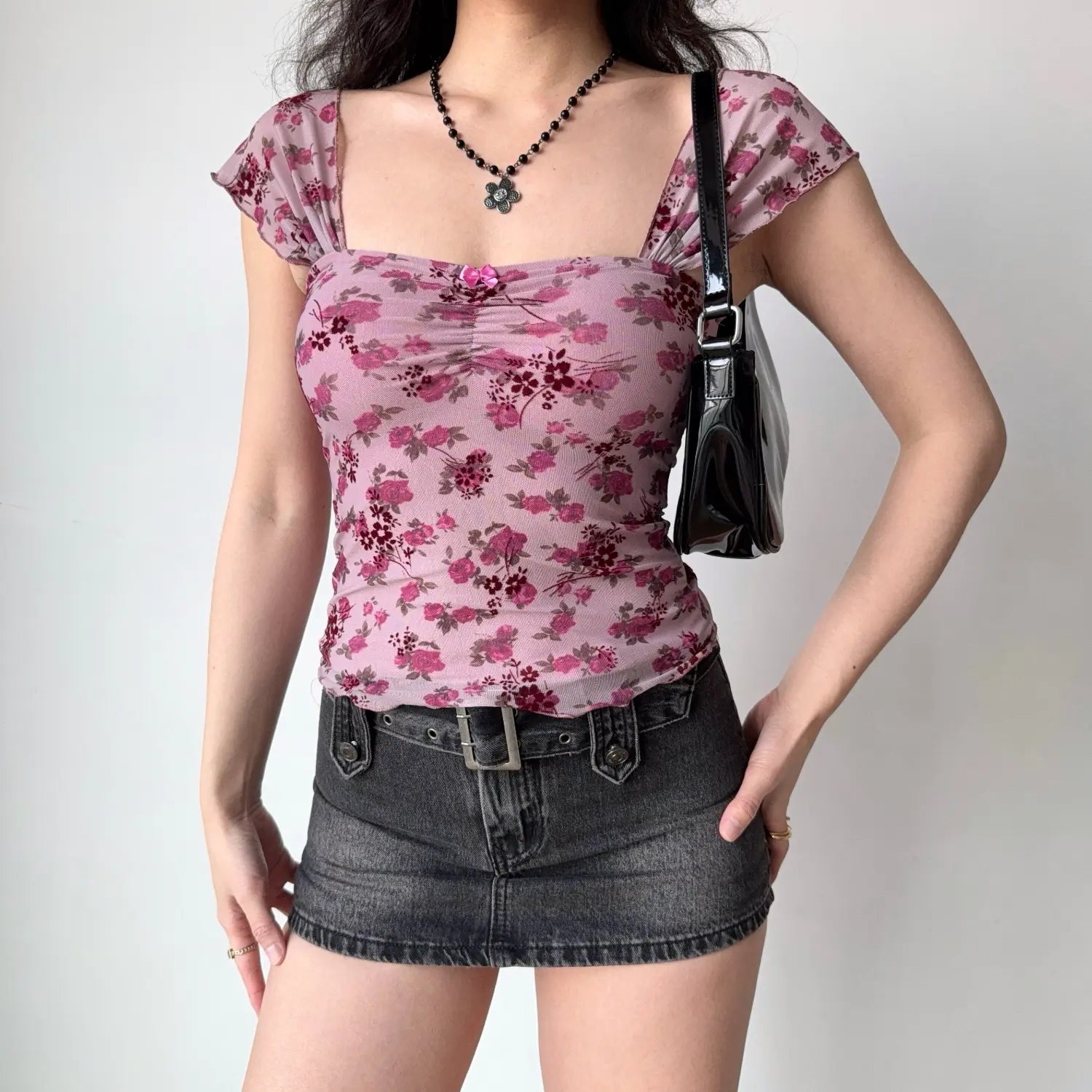 Full body lifestyle shot, model wearing pink floral mesh blouse matched with dark grey denim mini skirt